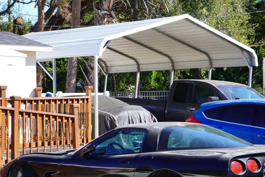 A metal carport stands next to a wooden deck and several parked vehicles — 2610 E DR MARTIN LUTHER KING JR BOULEVARD, TAMPA, FL