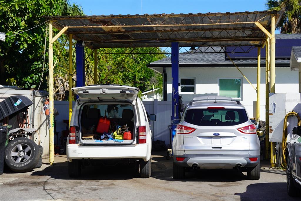 Two cars are parked under a metal carport structure in a residential backyard — 2610 E DR MARTIN LUTHER KING JR BOULEVARD, TAMPA, FL