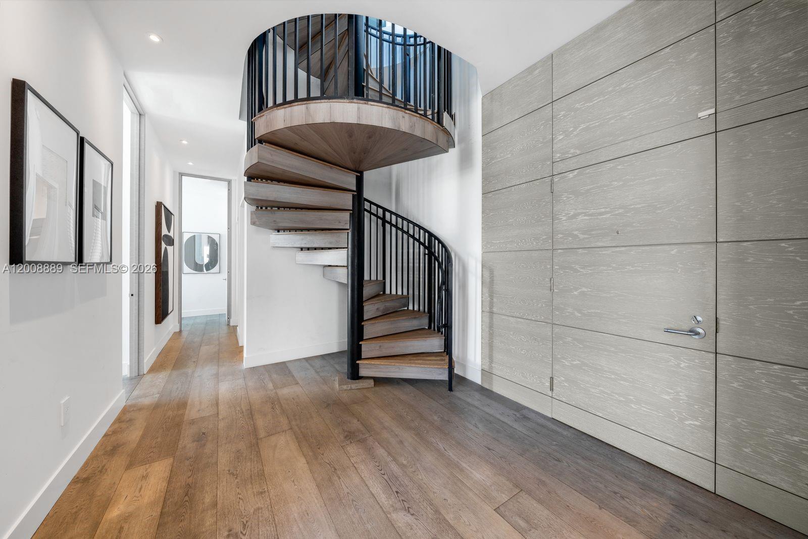 A spiral staircase with wooden treads and black railings stands in a modern hallway — 1300 S Miami Ave, Miami FL 33130, MIAMI, FL
