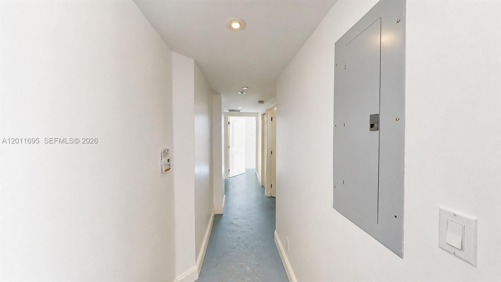 A narrow hallway features white walls, a blue floor, and a grey electrical panel — 111 E Flagler St # 705, Miami FL 33131, MIAMI, FL