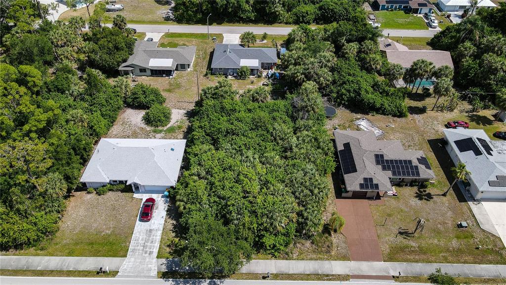 An aerial view shows a vacant, tree-covered lot situated between two residential houses — 23164 ELMIRA BOULEVARD, PUNTA GORDA, FL