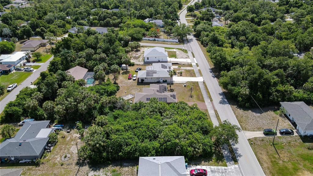 An aerial view shows several houses surrounded by dense trees and a paved road — 23164 ELMIRA BOULEVARD, PUNTA GORDA, FL