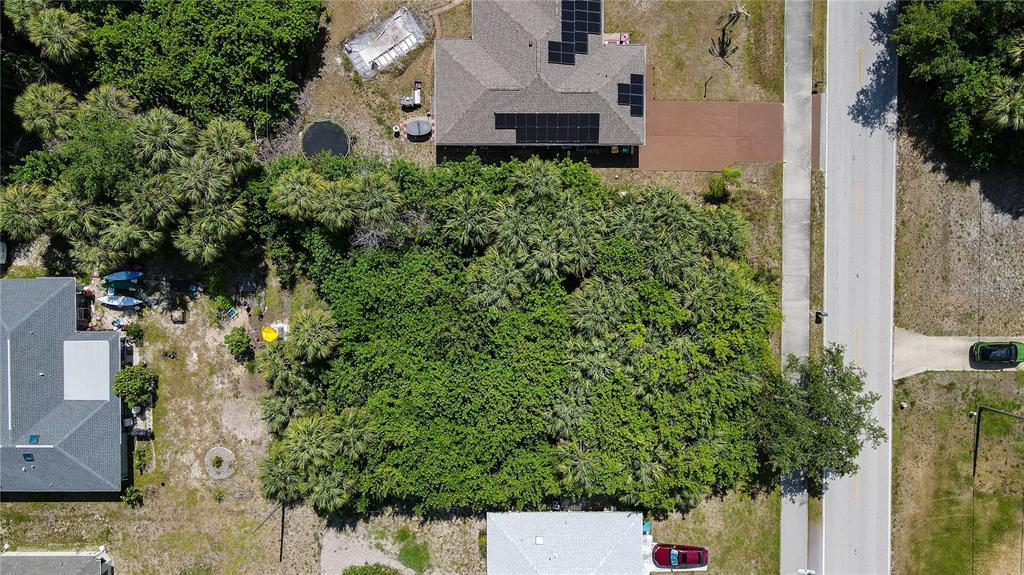 An aerial view shows a heavily wooded vacant lot situated between two residential properties — 23164 ELMIRA BOULEVARD, PUNTA GORDA, FL
