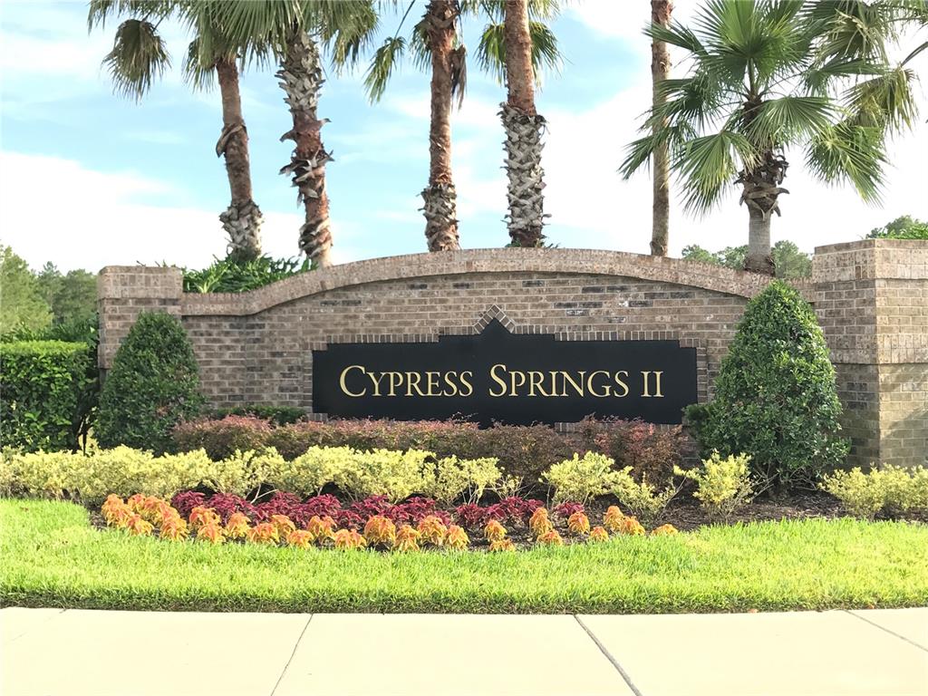 A brick monument sign for Cypress Springs II sits behind a landscaped garden with palm trees — 1702 CYPRESS RIDGE DRIVE, ORLANDO, FL