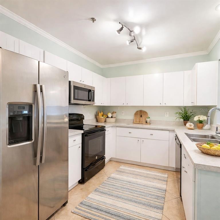 A kitchen features white cabinets, stainless steel appliances, and a granite countertop with a sink — 4865 CYPRESS WOODS DRIVE UNIT 2106, ORLANDO, FL
