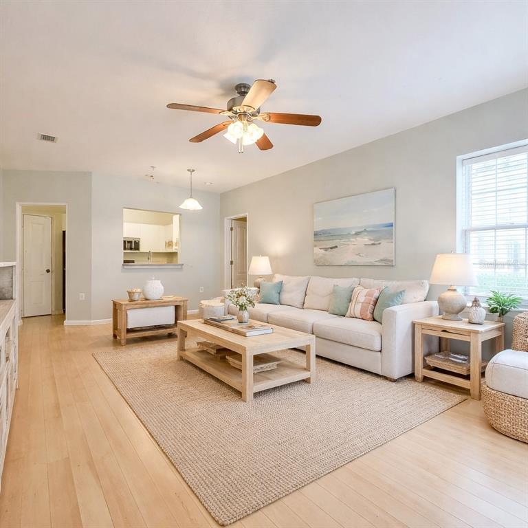 A living room features light wood floors, a beige sofa, and a ceiling fan — 4865 CYPRESS WOODS DRIVE UNIT 2106, ORLANDO, FL