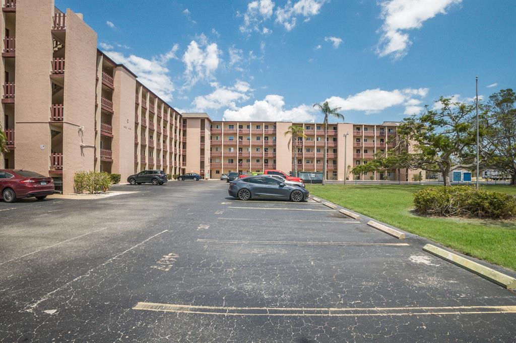 A multi-story apartment building with a parking lot in the foreground under a blue sky — 4015 LAKE BAYSHORE DRIVE UNIT 108, BRADENTON, FL