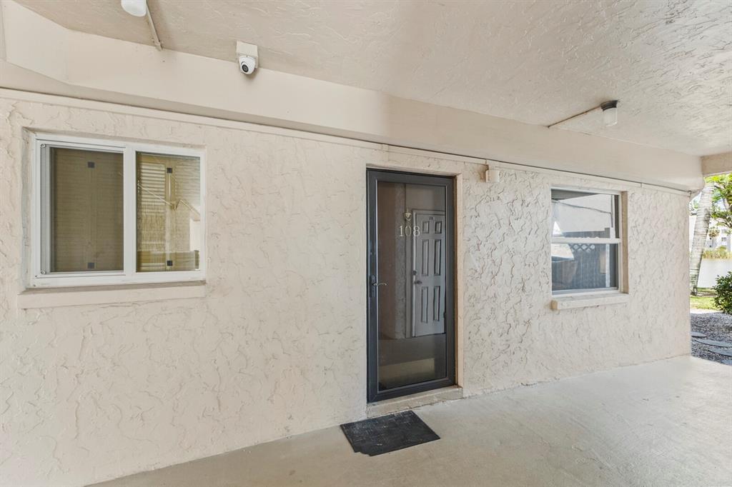 The exterior view shows a beige stucco wall with two windows and a front door — 4015 LAKE BAYSHORE DRIVE UNIT 108, BRADENTON, FL