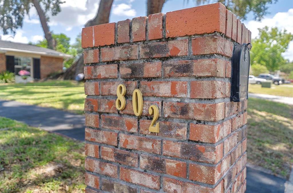 A brick mailbox pillar displays the house number 802 in front of a residential lawn — 802 HASTINGS DRIVE, KISSIMMEE, FL