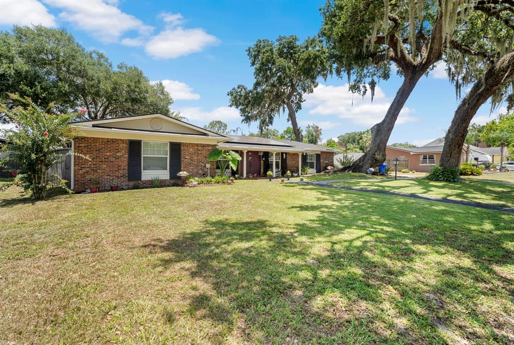 A single-story brick house with a large front lawn and mature oak trees — 802 HASTINGS DRIVE, KISSIMMEE, FL