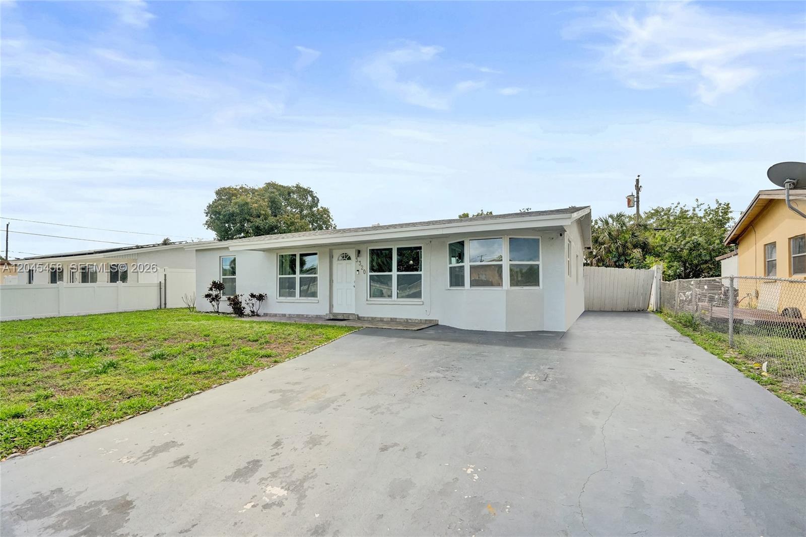 A single-story white house with a concrete driveway and a front lawn — 3320 NW 18th St, Lauderhill FL 33311, LAUDERHILL, FL
