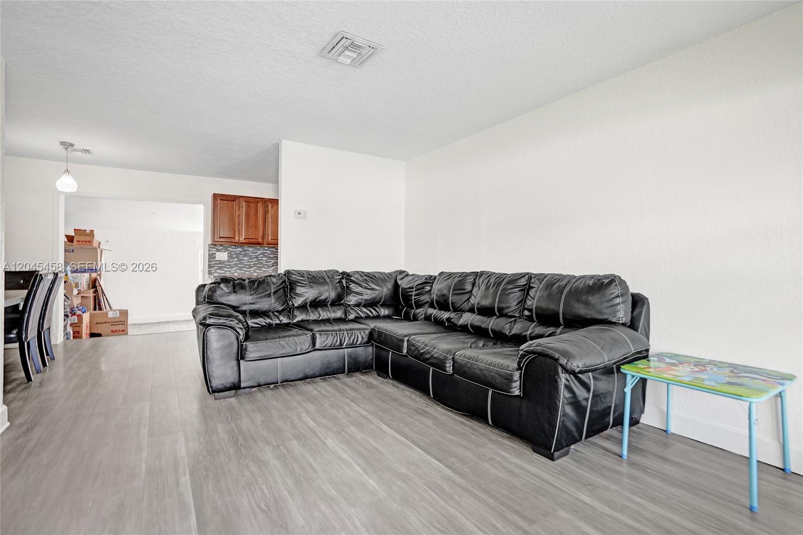 A living room features a black sectional sofa, light wood-look flooring, and white walls — 3320 NW 18th St, Lauderhill FL 33311, LAUDERHILL, FL