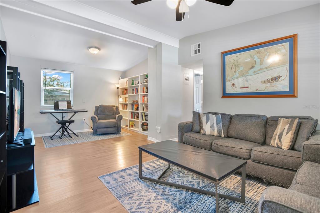 A living room features light wood flooring, a gray sofa, a bookshelf, and a keyboard stand — 5450 ROSE AVENUE, ORLANDO, FL