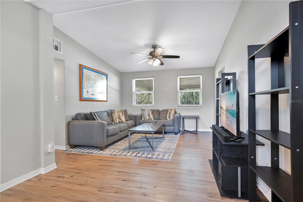 A living room features gray sofas, a coffee table, wood-look flooring, and a ceiling fan — 5450 ROSE AVENUE, ORLANDO, FL