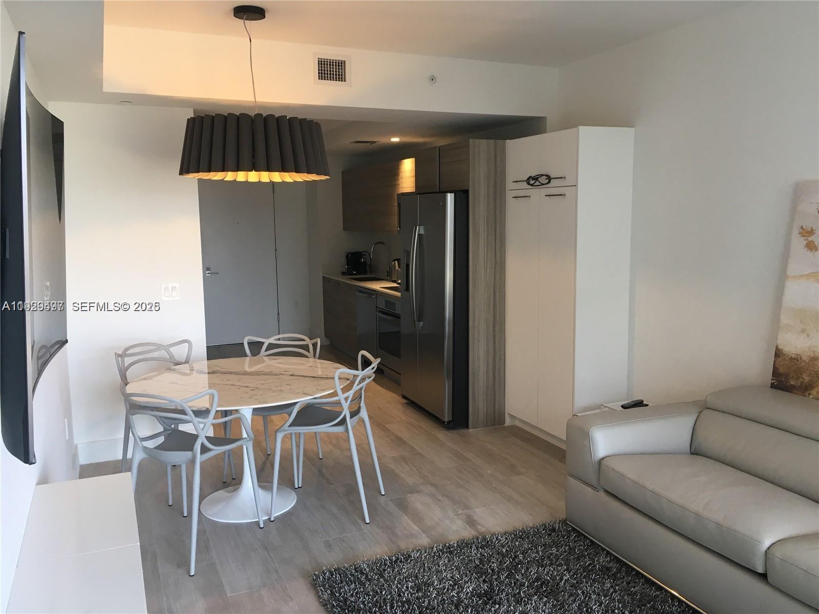 A modern open-concept kitchen and dining area features a marble table and stainless steel appliances — 121 NE 34th St # 1203, Miami FL 33137, MIAMI, FL