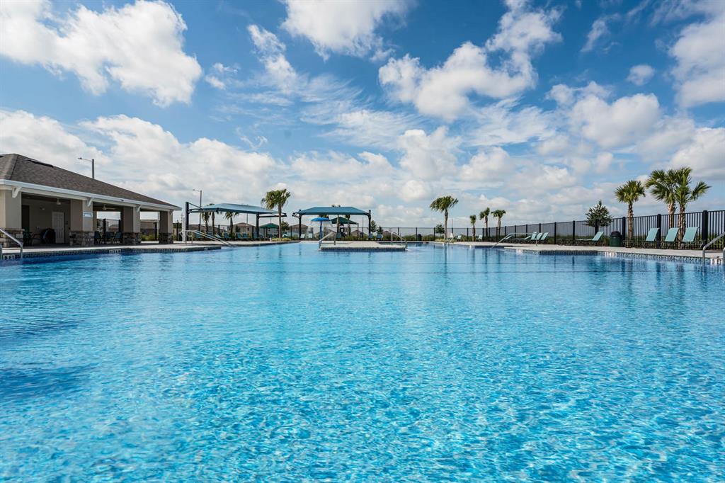 A large outdoor swimming pool with a covered patio area and palm trees under clouds — 2518 MARIAH PLACE, LAKE ALFRED, FL