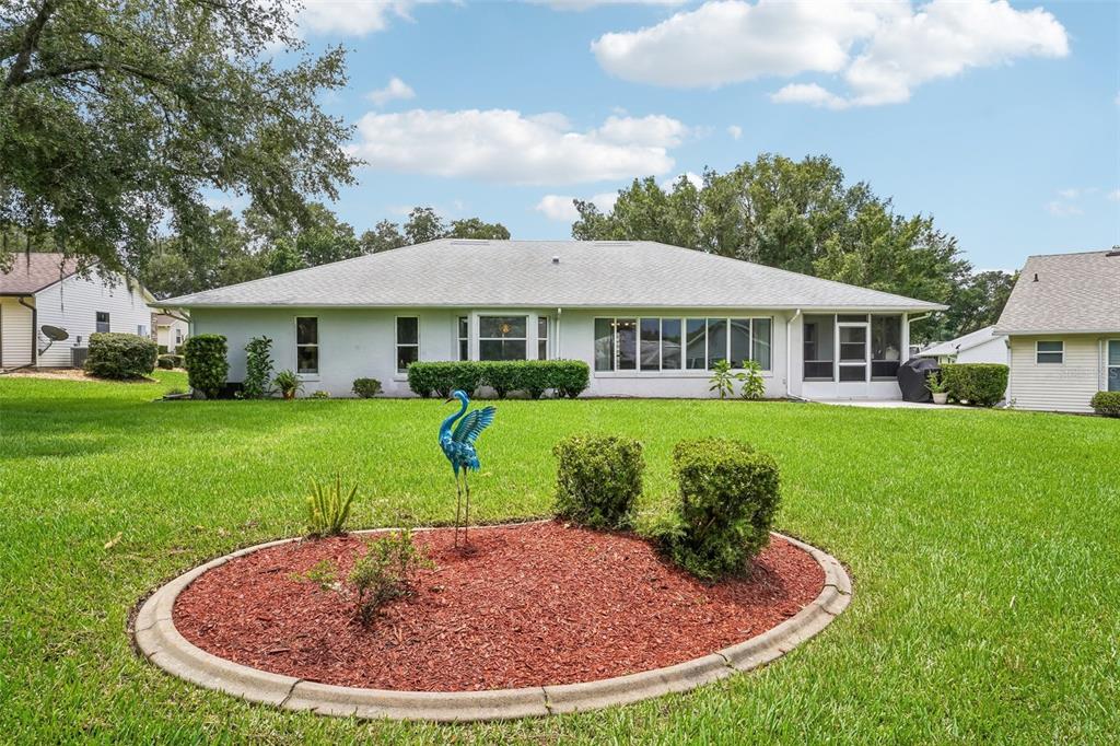 A single-story house with a white exterior, a screened-in porch, and a landscaped garden bed — 6407 TILDON COURT, LEESBURG, FL