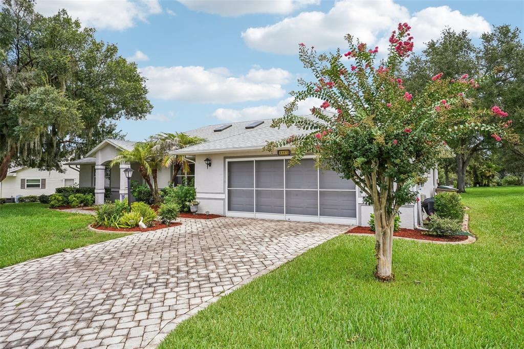 A single-story house with a paved driveway, a screened garage, and a blooming crape myrtle — 6407 TILDON COURT, LEESBURG, FL