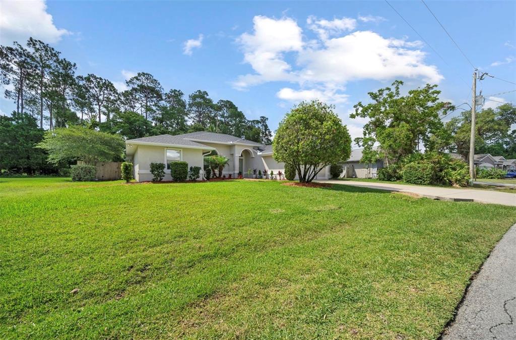 A single-story house with a light-colored exterior, a large front lawn, and a concrete driveway — 10 FORTRESS PLACE, PALM COAST, FL