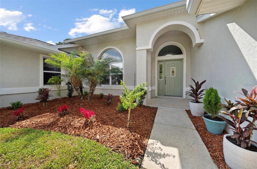 A light-colored house exterior features a green front door, arched windows, and a landscaped yard — 10 FORTRESS PLACE, PALM COAST, FL