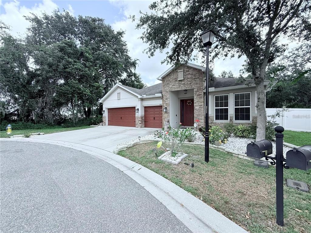 A single-story house with a stone facade, two garage doors, and a front yard — 6456 DOE PATH COURT, WESLEY CHAPEL, FL