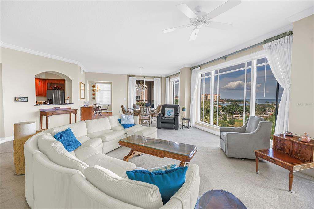 A spacious living room features a white sectional sofa, large windows with water views, and carpet — 100 BEACH DRIVE NE UNIT 702, ST PETERSBURG, FL