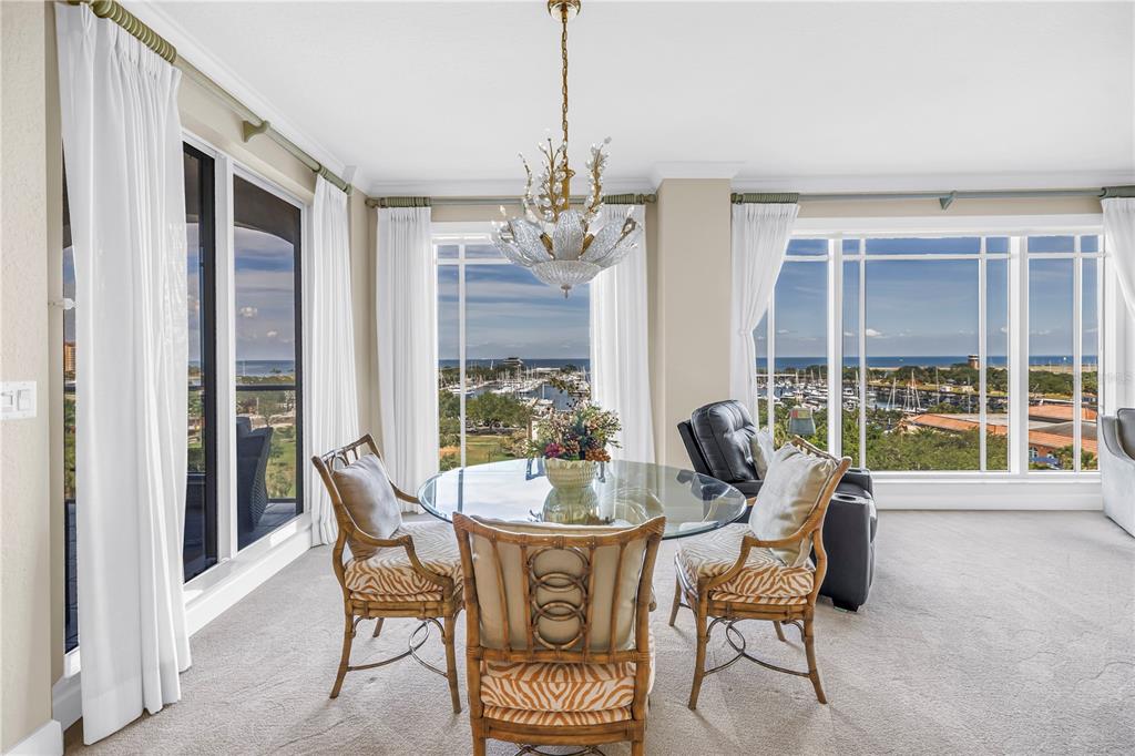 A dining area with a glass table, rattan chairs, and large windows overlooking a marina — 100 BEACH DRIVE NE UNIT 702, ST PETERSBURG, FL