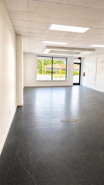 An empty commercial space features a drop ceiling, dark flooring, and a large front window — 4207 EDGEWATER DRIVE, ORLANDO, FL