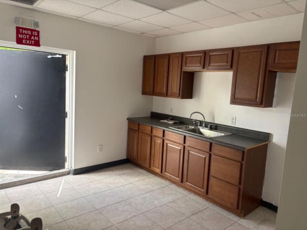 A kitchenette with wooden cabinets, a sink, and a black door labeled not an exit — 4207 EDGEWATER DRIVE, ORLANDO, FL