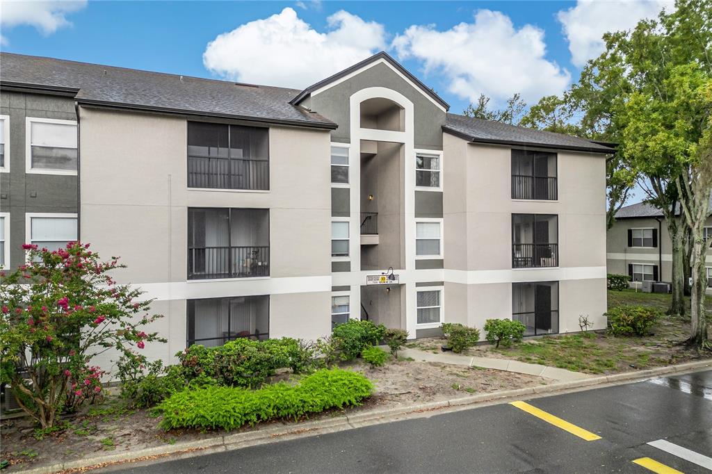 A three-story apartment building with screened balconies and a central recessed stairwell entrance — 7511 SEURAT STREET UNIT 10102, ORLANDO, FL