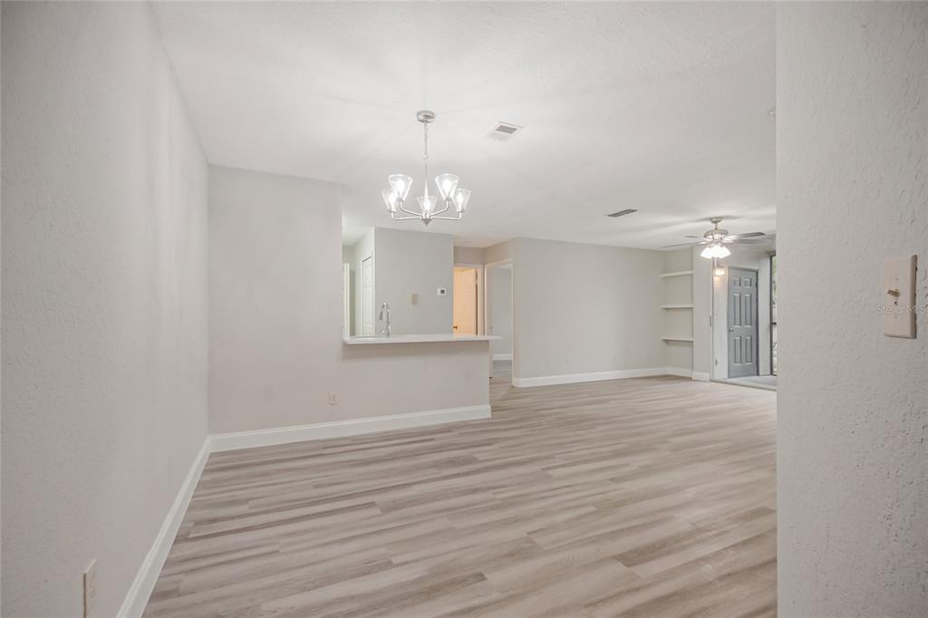 An open-concept living and dining area features light wood-look flooring and a breakfast bar — 7511 SEURAT STREET UNIT 10102, ORLANDO, FL