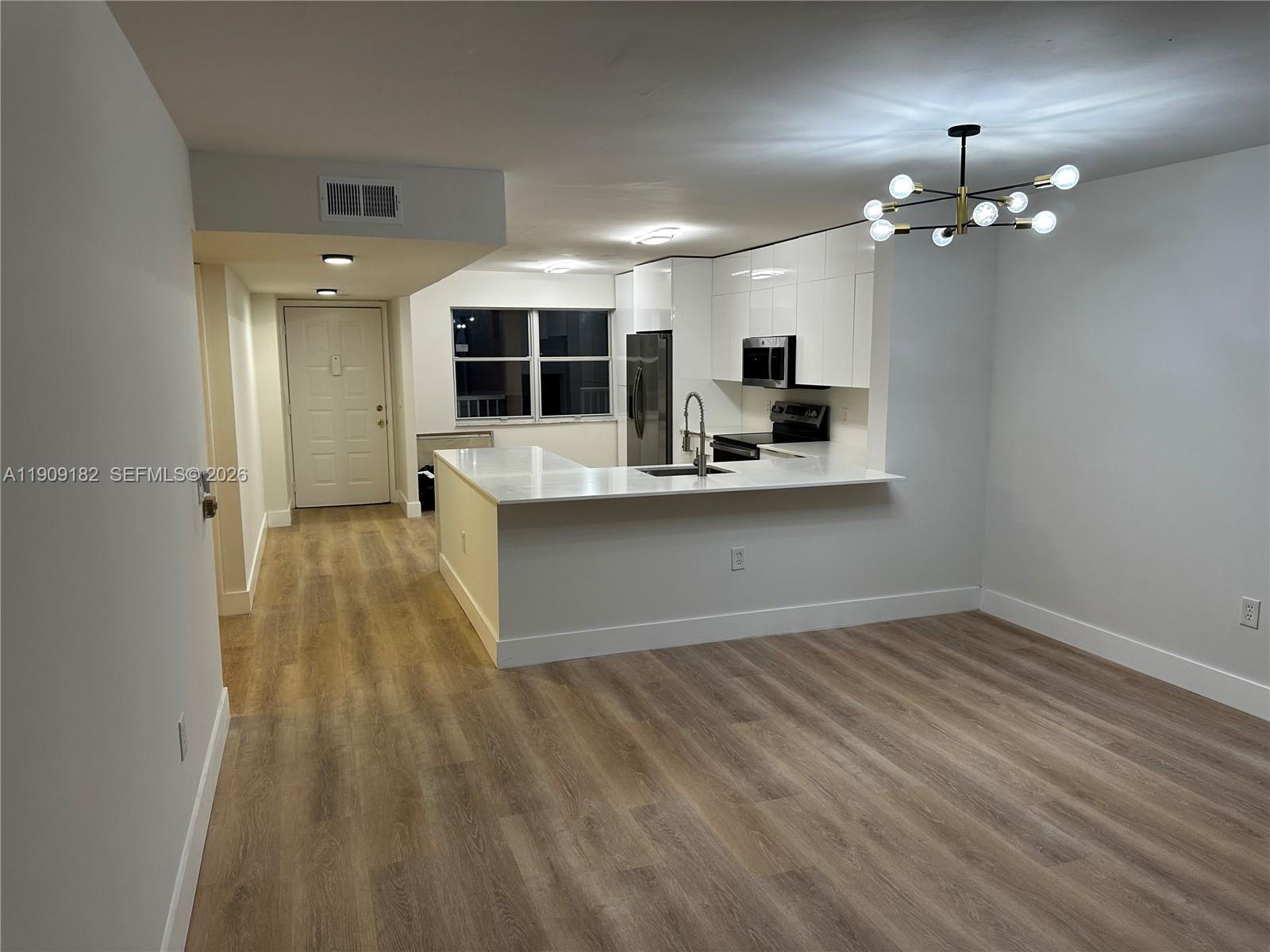 An open-concept kitchen features white cabinetry, stainless steel appliances, and a peninsula counter — 2560 NW 103rd Ave # 402, Sunrise FL 33322, SUNRISE, FL