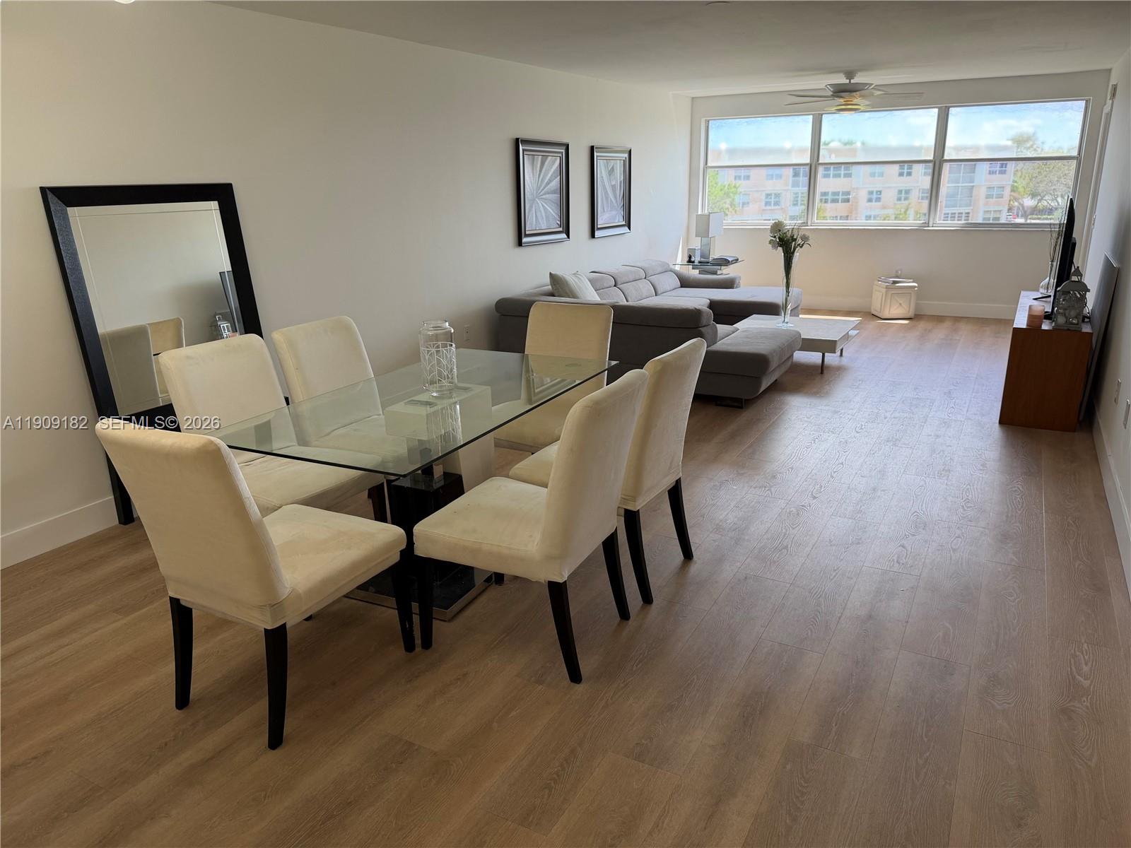 An open-concept living and dining area features light wood flooring and a glass dining table — 2560 NW 103rd Ave # 402, Sunrise FL 33322, SUNRISE, FL