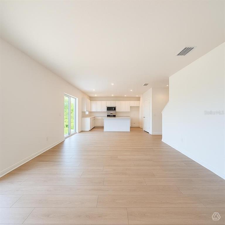An open-concept kitchen and living area features white cabinetry, a center island, and light-colored flooring — 12926 RED DEER PLACE, PARRISH, FL