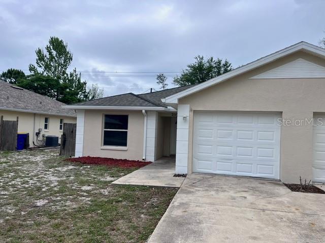 A tan single-story house features a white garage door and a concrete driveway — 2115 INDIA PALM DRIVE, EDGEWATER, FL