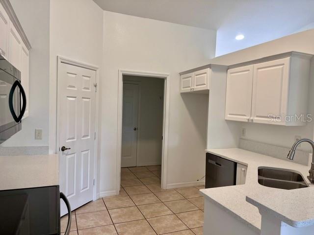 A kitchen with white cabinets, light countertops, tile flooring, and a doorway to another room — 2115 INDIA PALM DRIVE, EDGEWATER, FL