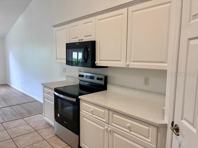 A kitchen features white cabinets, a stainless steel stove, a microwave, and light-colored countertops — 2115 INDIA PALM DRIVE, EDGEWATER, FL