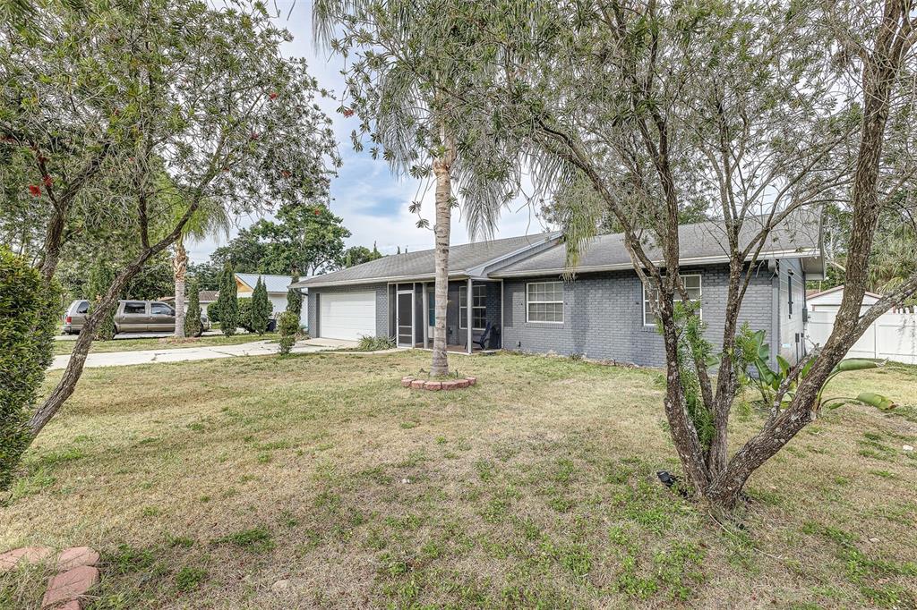 A single-story gray brick house with a white garage door and a front yard — 408 LAKE NED, WINTER HAVEN, FL