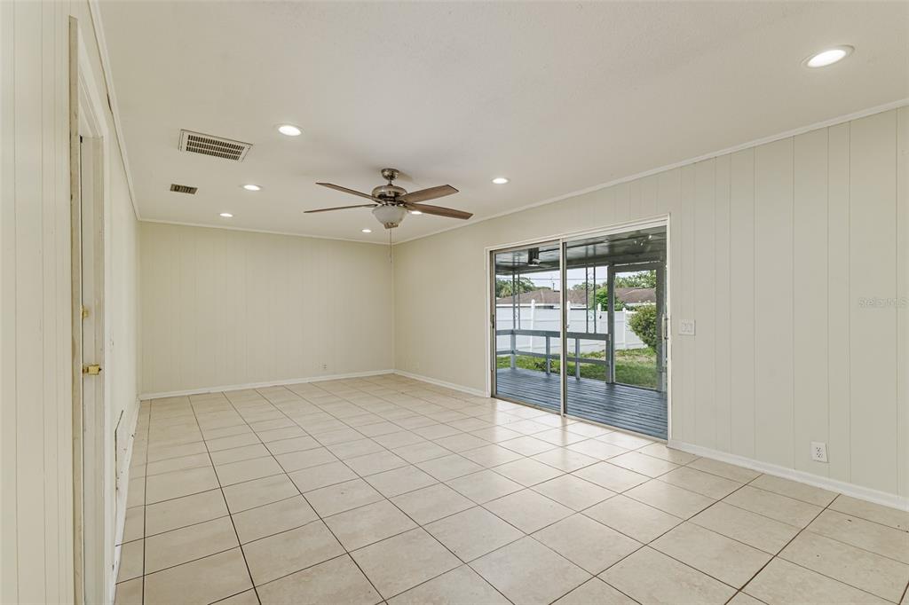 An empty room with beige tile flooring, a ceiling fan, and sliding glass doors — 408 LAKE NED, WINTER HAVEN, FL
