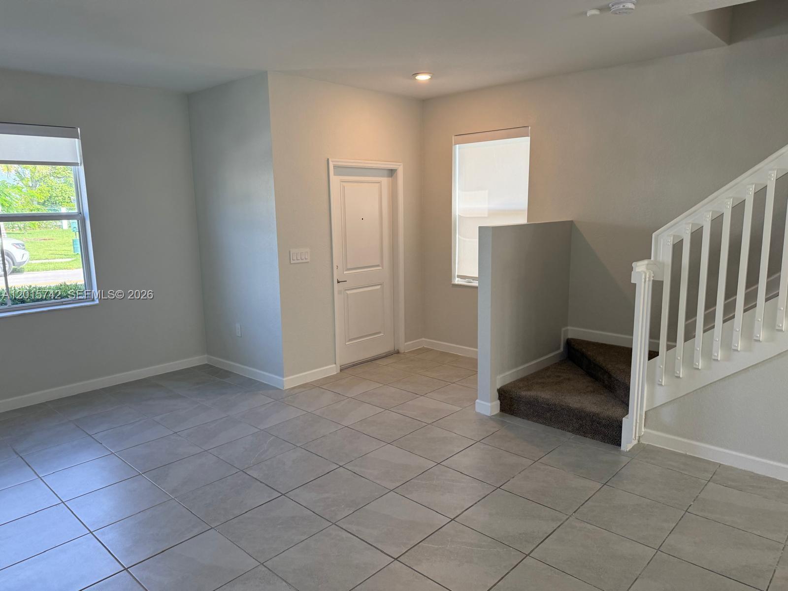 An entryway features light gray tile flooring, a white front door, and a carpeted staircase — 1884 SE 27th Rd # 1884, Homestead FL 33035, HOMESTEAD, FL