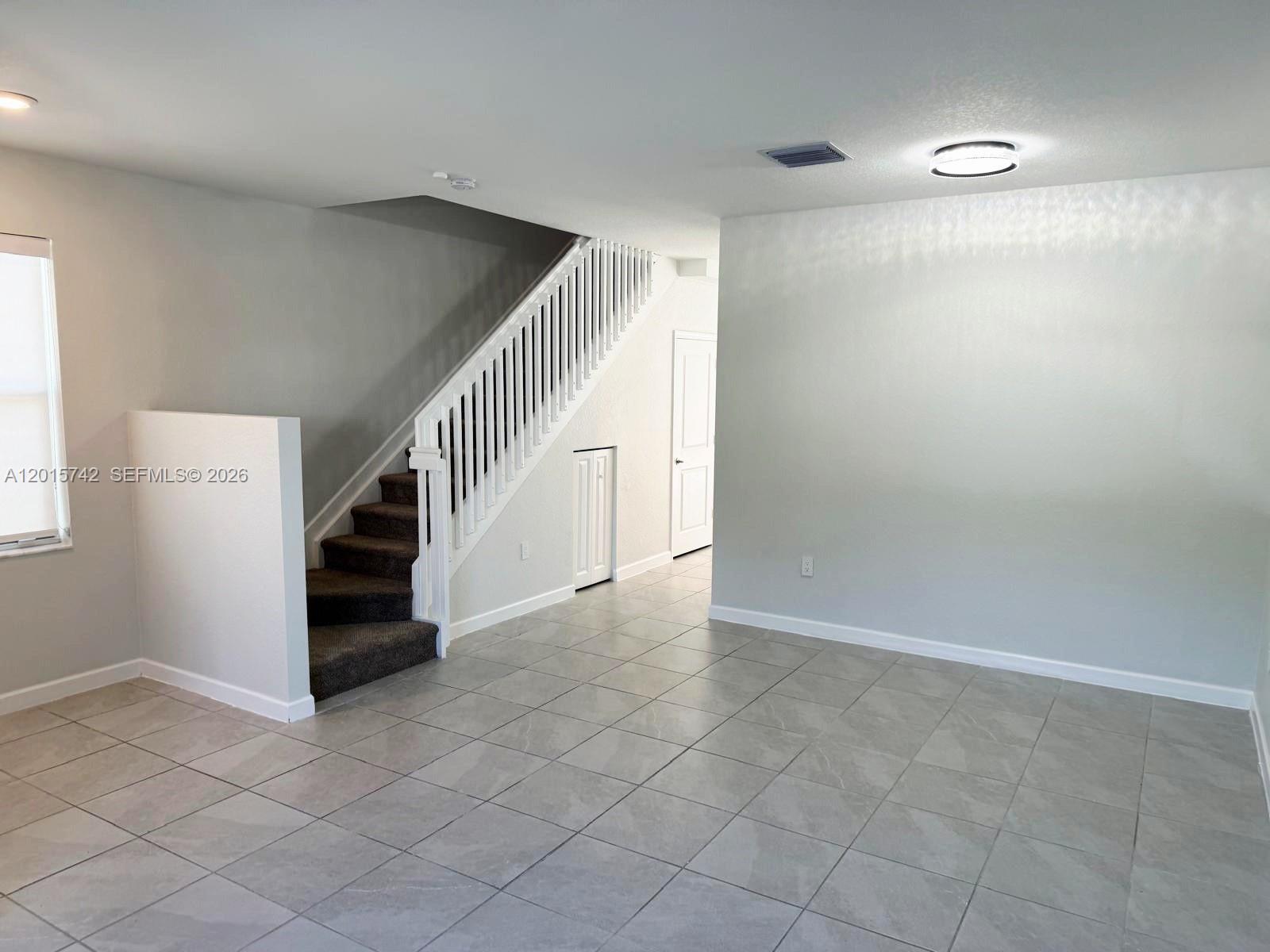 An interior view shows a room with tiled floors, a staircase, and light-colored walls — 1884 SE 27th Rd # 1884, Homestead FL 33035, HOMESTEAD, FL
