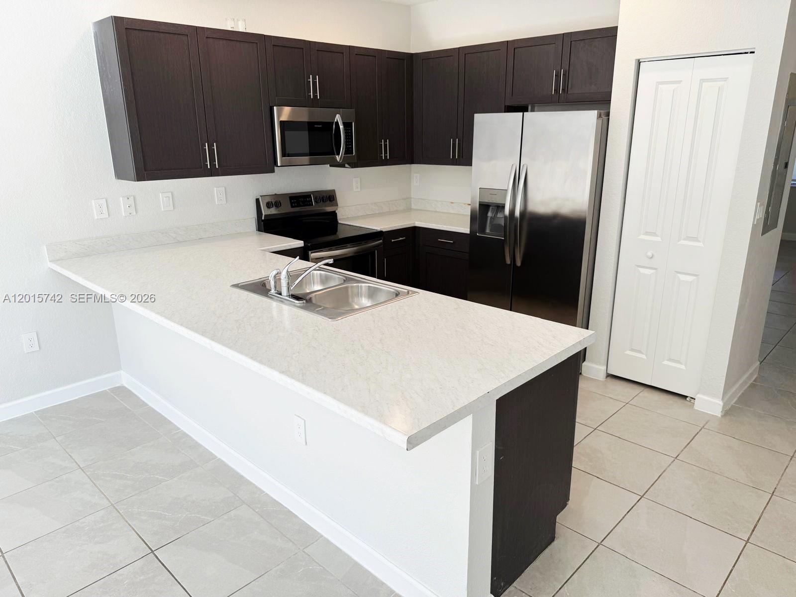 A kitchen features dark wood cabinets, stainless steel appliances, and a white quartz countertop island — 1884 SE 27th Rd # 1884, Homestead FL 33035, HOMESTEAD, FL