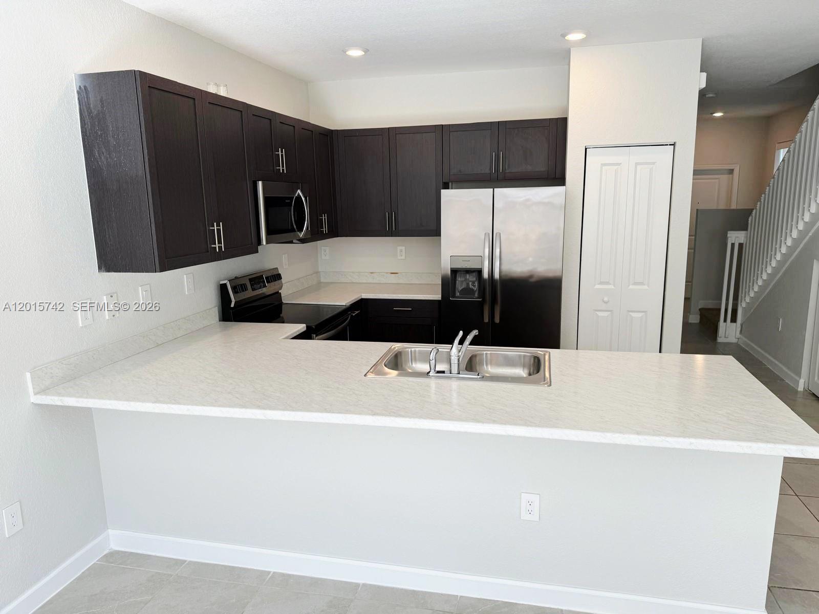 A kitchen features dark wood cabinets, stainless steel appliances, and a white countertop peninsula — 1884 SE 27th Rd # 1884, Homestead FL 33035, HOMESTEAD, FL