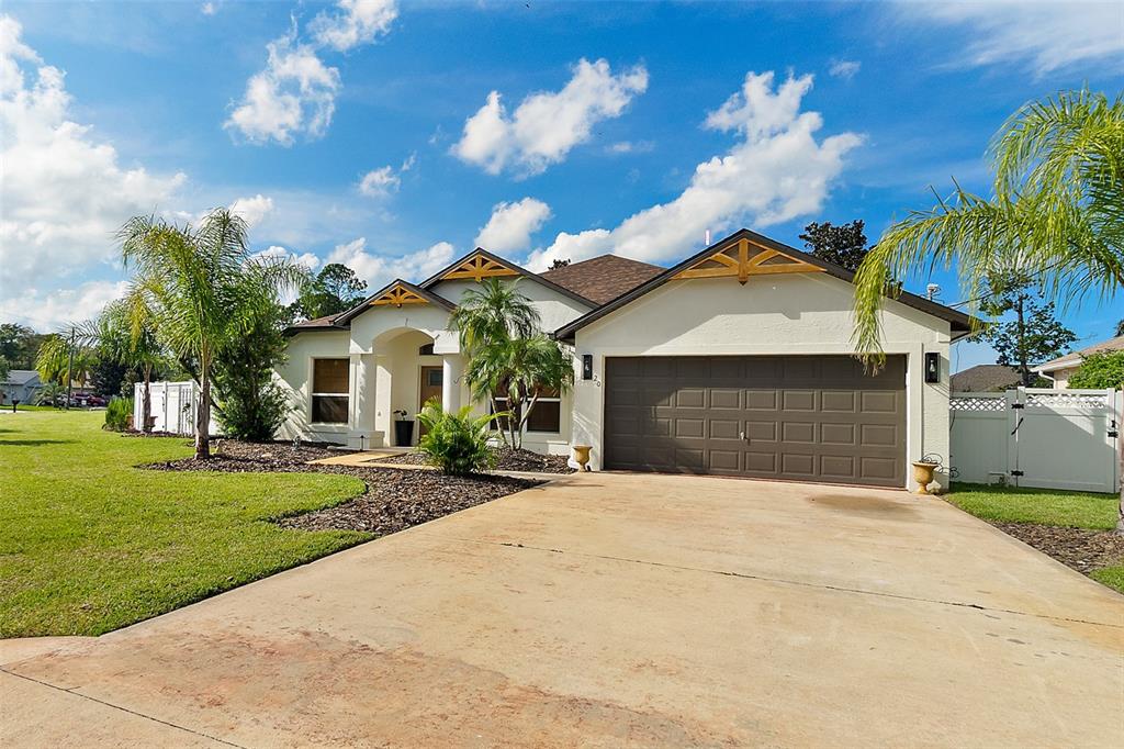 A single-story house with a brown garage door, light-colored stucco, and decorative wooden gable accents — 20 EASTWOOD DRIVE, PALM COAST, FL