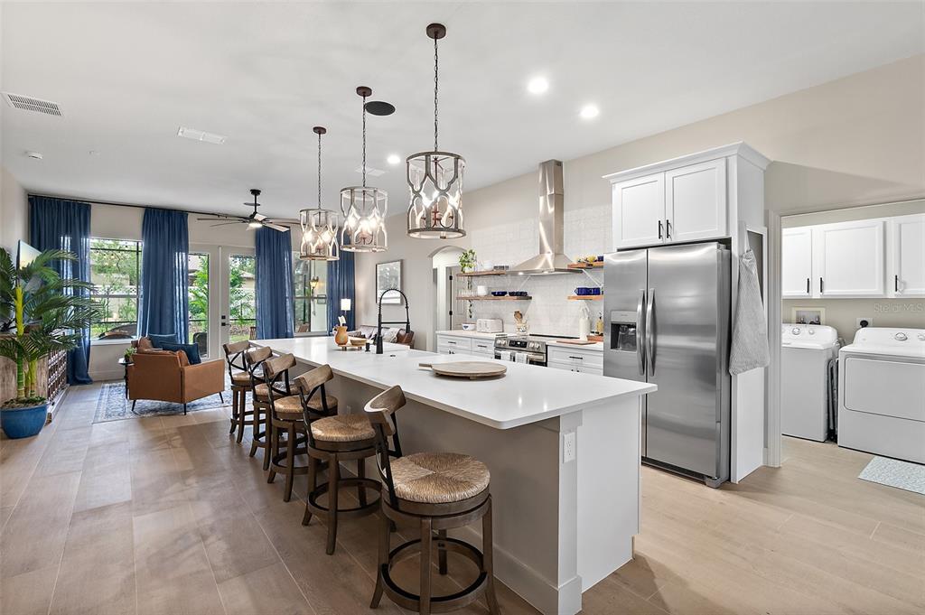 A modern kitchen features a large white island, stainless steel appliances, and pendant lighting — 20 EASTWOOD DRIVE, PALM COAST, FL