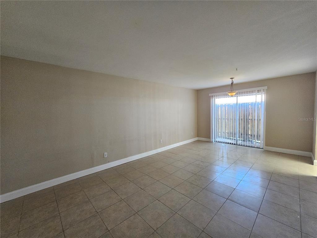 An empty room with beige walls, tile flooring, and a sliding glass door to a patio — 7602 POWHATAN AVENUE W UNIT 3, TAMPA, FL
