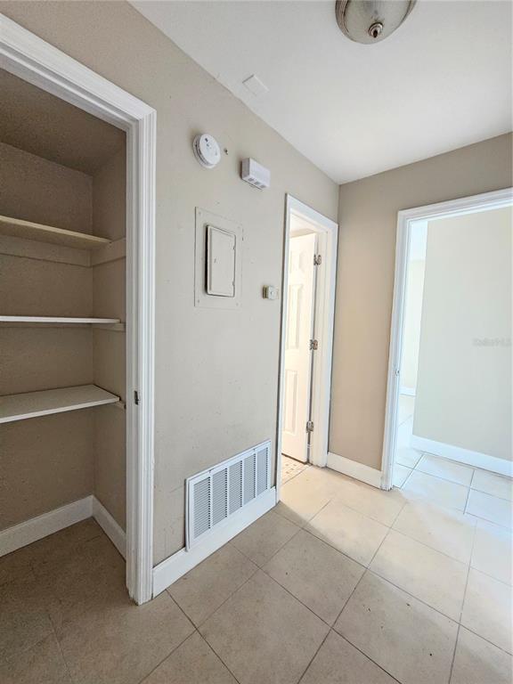 A hallway features a built-in closet with shelves, tile flooring, and two doorways — 7602 POWHATAN AVENUE W UNIT 3, TAMPA, FL