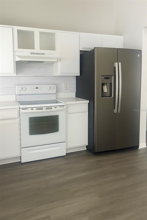 A kitchen features white cabinets, a white electric stove, and a dark stainless steel refrigerator — 1293 COURTLAND BOULEVARD, DELTONA, FL