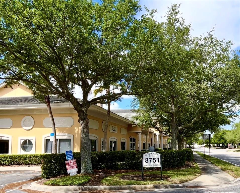 A low-rise commercial building with yellow stucco walls is surrounded by mature trees and landscaping — 8751 COMMODITY CIRCLE UNIT 4, ORLANDO, FL