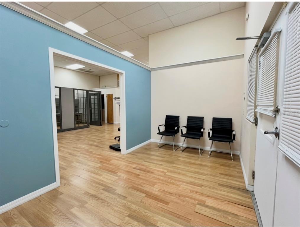 A waiting area with three black chairs, light wood flooring, and a blue accent wall — 8751 COMMODITY CIRCLE UNIT 4, ORLANDO, FL